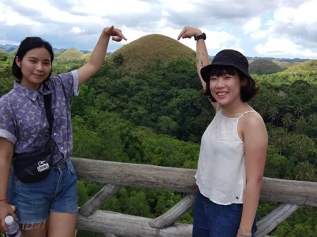Two tourists posing and pointing at the famous Chocolate Hills in Bohol