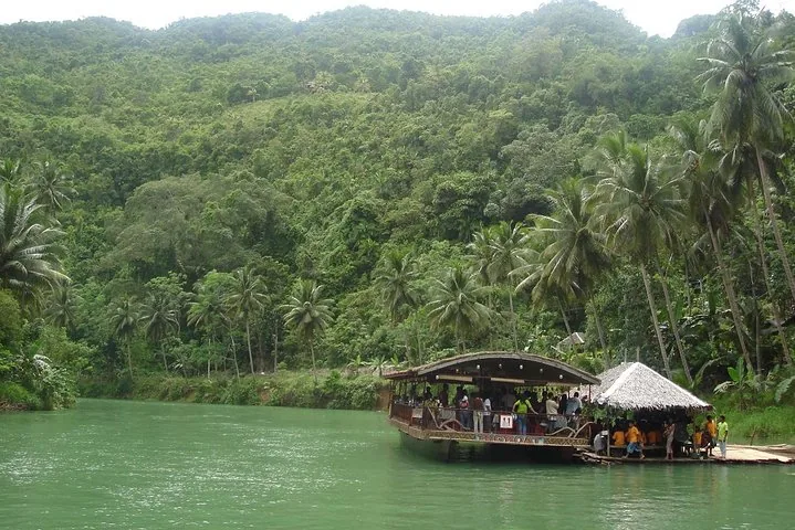 Ein großes Flussausflugsboot an einer Station, umgeben von tropischem Wald.